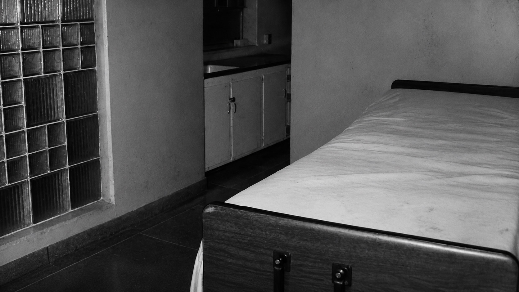 Monochrome editorial rendering of a bed and worn hospital interior based on the migrated reference.