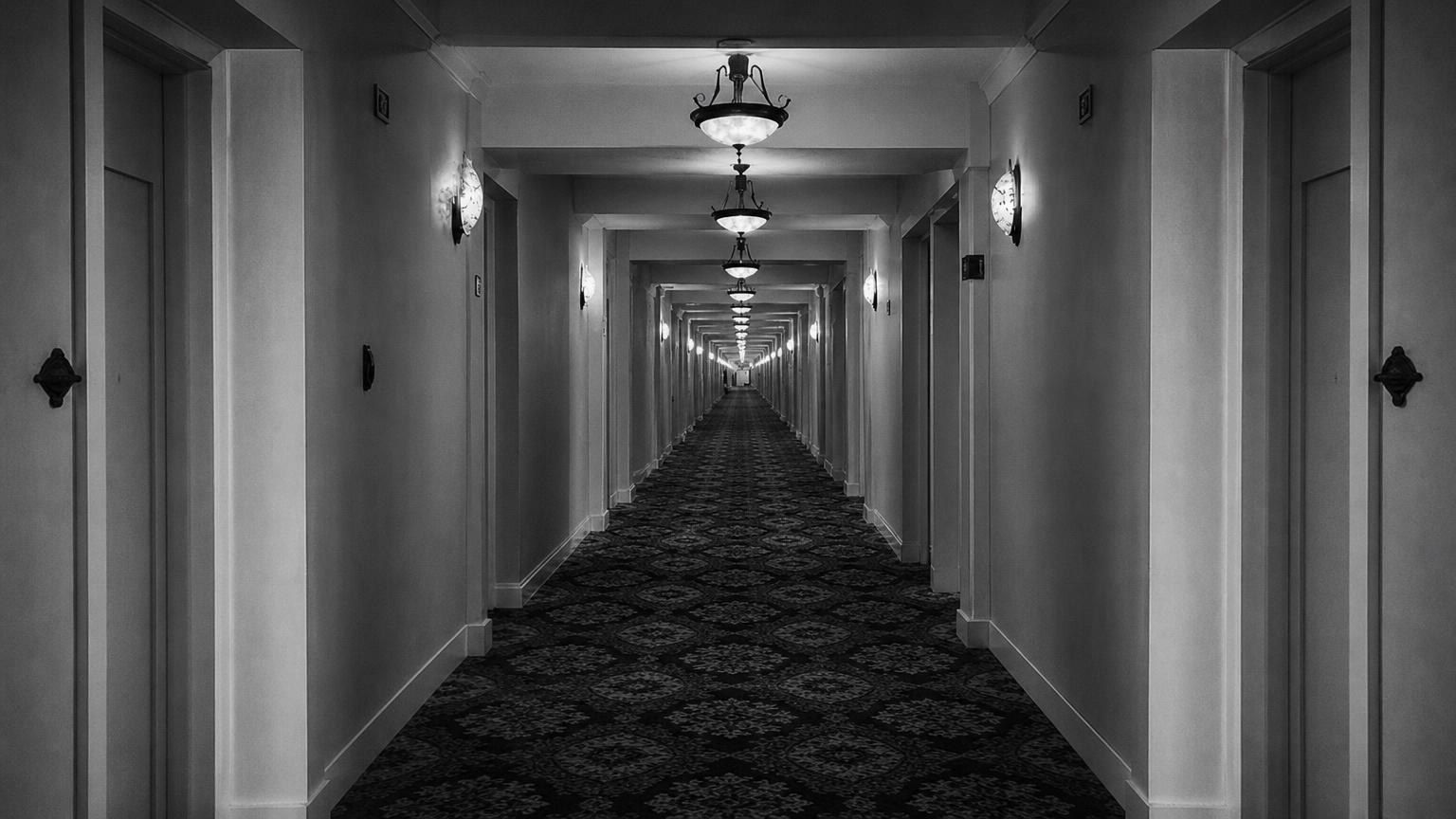 Monochrome editorial rendering of a French Lick Springs Hotel corridor with ceiling lights and patterned carpet.