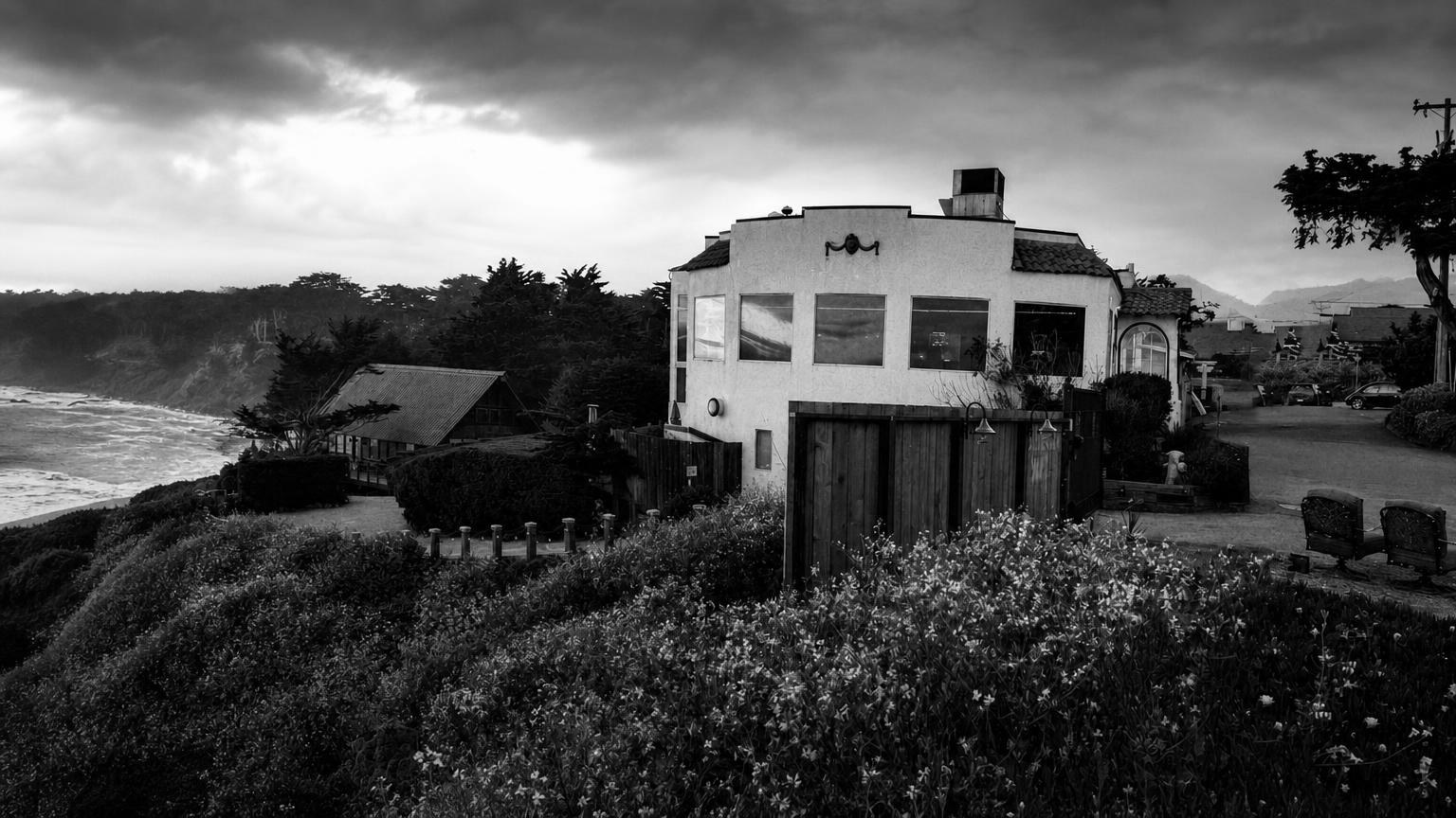 Monochrome editorial rendering of Moss Beach Distillery's exterior above the coast.