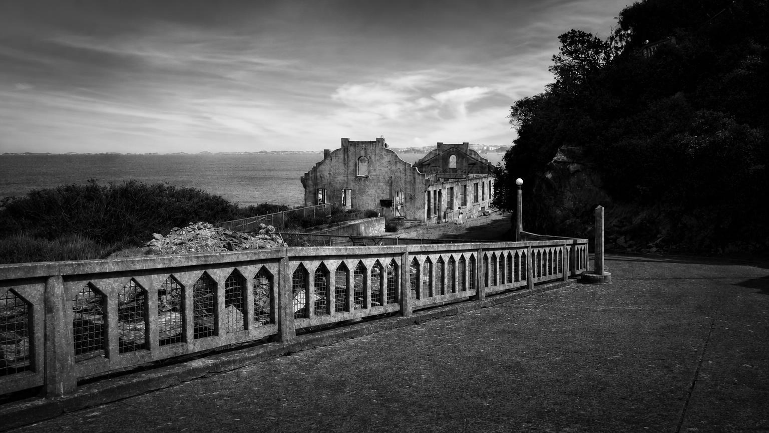 Monochrome editorial rendering of Alcatraz ruins beyond a stone balustrade, overlooking the bay.