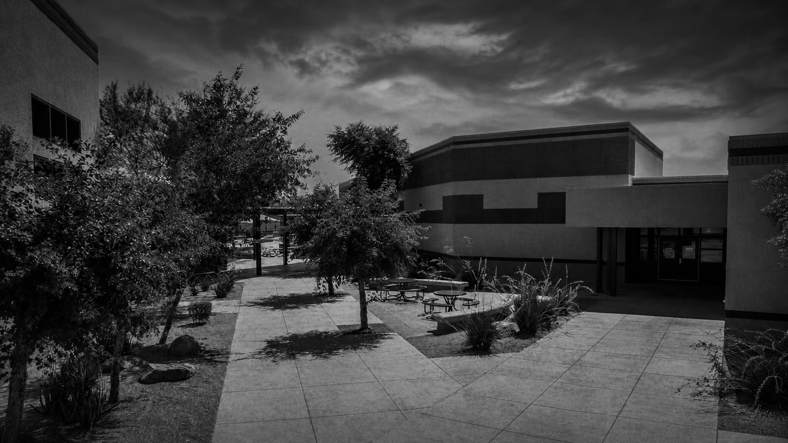 Monochrome editorial rendering of the Deer Valley High School courtyard and low campus buildings.