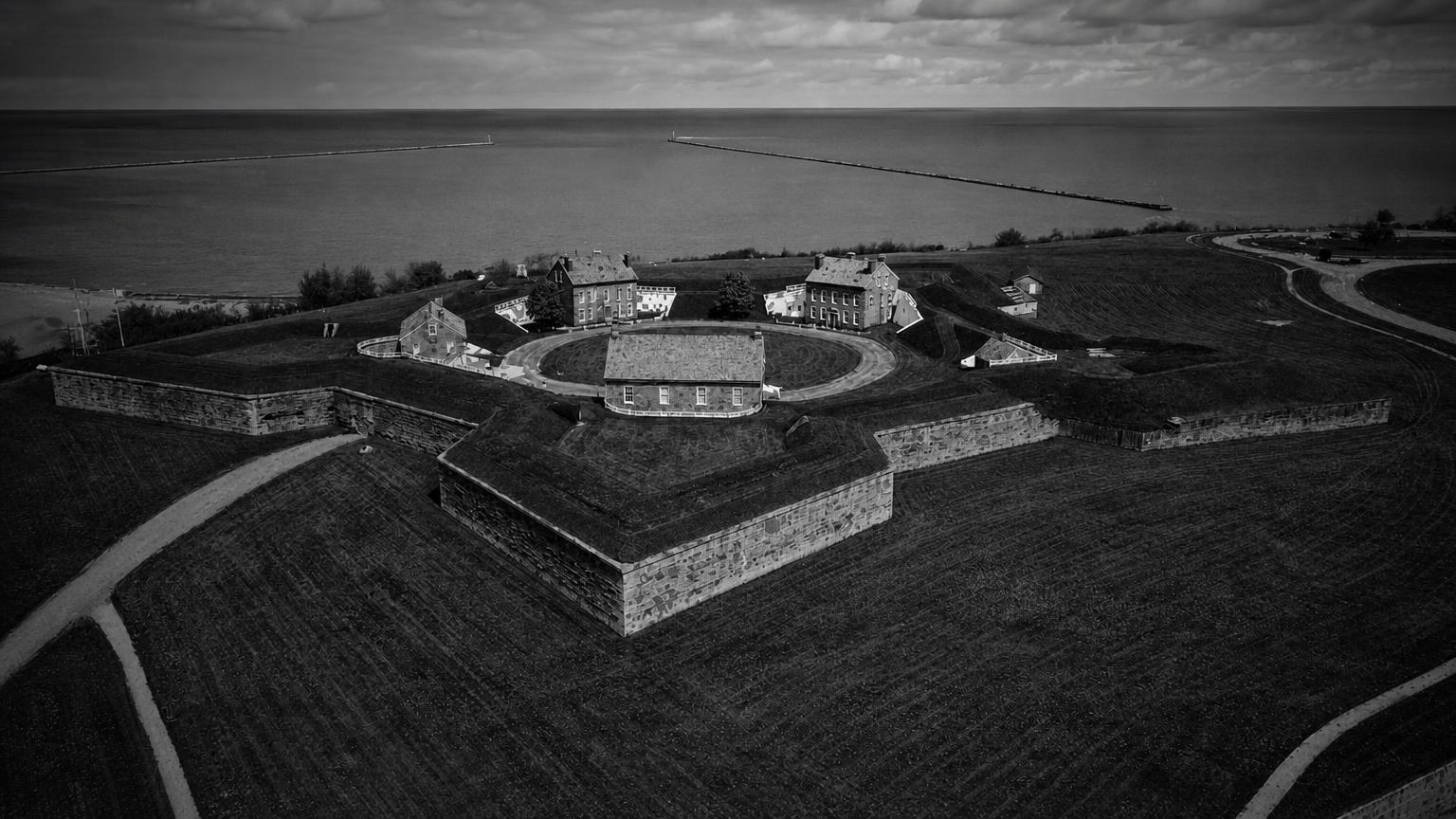 Monochrome editorial rendering of Fort Ontario's defensive walls and buildings beside Lake Ontario.